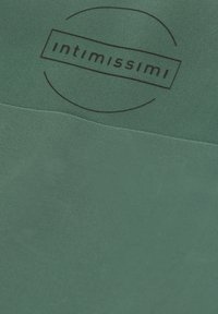 Grön tyg med en slät textur har en cirkulär svart logotyp som säger "intimissimi." Designen är enkel och minimalistisk.