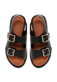 Black slip-on sandals featuring two wide straps with gold buckles. The insole is brown, and the texture is smooth. Rounded shape, open sides.