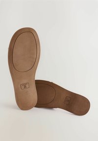 Brown shoe uppers with a smooth texture and flat soles. The soles feature a branded imprint and a rounded toe shape.