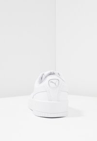 Vit Puma-sneaker sedd från hälen, som visar logotypen på den vadderade kragen och den tjocka gummisulans på en enkel vit yta.