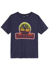 Navyblå bomull t-shirt med ett cirkulärt grafiskt motiv av ett träd och "Timberland"-logotypen i orange och gula nyanser. Kortsleeves.