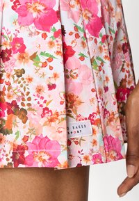 Floral skirt with a mix of pink, orange, and green patterns. Made of lightweight fabric, features pleats and a corner label that reads "Ted Baker SPORT."