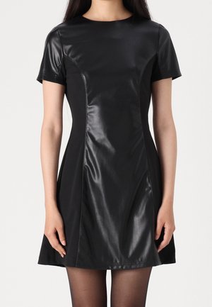 Zwarte jurk met een nauwsluitend lijfje en een uitlopende rok. Korte mouwen van glad leer; de rest is een zachte stof met een matte afwerking.