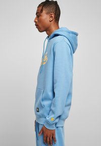 Felpa leggera blu con tasca frontale, cappuccio con cordino e logo giallo. Polsini e orlo a costine, realizzata in morbido misto cotone.