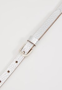 Ceinture en cuir blanc avec une finition texturée, dotée d'une boucle en métal argenté et d'un passant. Comprend plusieurs trous pour un ajustement.