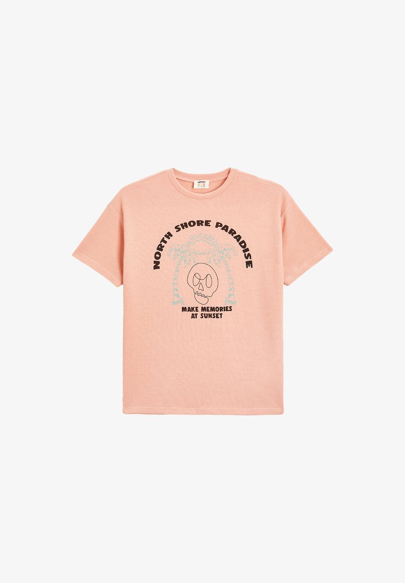 Lyserød t-shirt med korte ærmer, der har en struktureret tekstur og et trykt design med teksten "NORTH SHORE PARADISE" samt et kraniumgrafik.