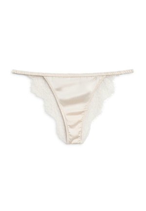 String en satin beige avec délicate bordure en dentelle blanche sur les côtés et fine ceinture élastique, posé à plat sur fond blanc.