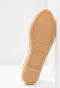 Semelle d'une espadrille marron clair avec la taille 37 indiquée, montrant un talon en caoutchouc texturé et une semelle avant lisse.