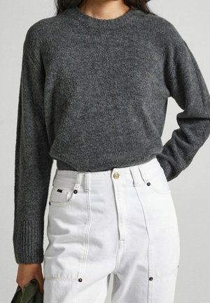 Pull gris en tricot avec un col rond et des poignets côtelés, associé à un pantalon blanc taille haute avec des accents de boutons en métal et des poches.