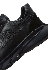 Zapatillas negras de cuero con paneles texturizados, una puntera lisa y una suela de goma flexible con detalles en patrón de ola.