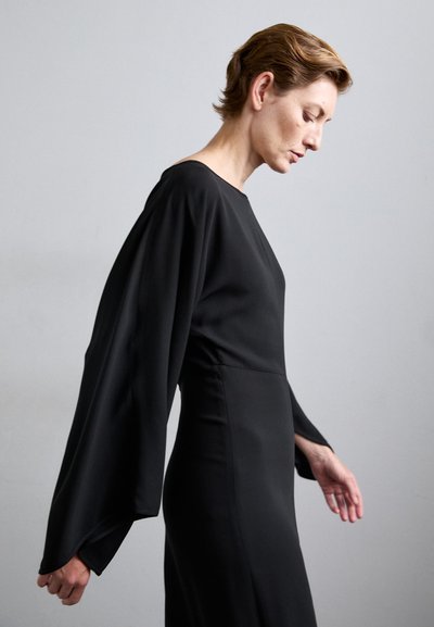 Black long-sleeve dress with a straight silhouette, made of smooth fabric. Features wide sleeves and a high neckline, minimalistic design.