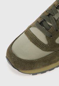 Õliva rohelised tennised, mis on valmistatud seas siidse seemisnaha ja nailonist, ümarate ninadega, tekstuursete paelade ja vastupidava kummist taldaga.