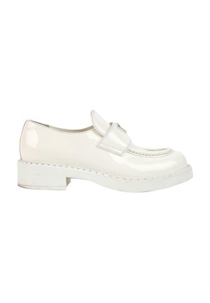 Mocassin en cuir verni blanc avec une semelle épaisse et une large bride sur le dessus, présenté en profil latéral sur fond blanc.