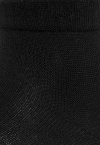 Schwarze gerippte Knöchelsocke mit einem strukturierten Strickmuster und einem eng anliegenden Bündchen. Das Material ist weich und elastisch, entworfen für Komfort und Passform.