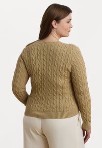 Kabelstrikket genser i beige, laget av teksturert stoff med rund hals og vrangbord, med lange ermer og en tettsittende silhuett.