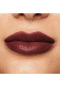 Labios burdeos mate y profundos con una textura suave que destacan por su forma voluptuosa, contra un fondo de tono de piel claro.