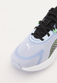 Light blue athletic shoe with black laces, mesh upper, and white logo. Features green accents and textured details, designed for comfort.