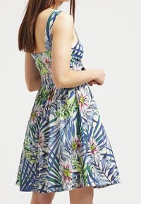 Robe à motifs floraux avec un corsage ajusté et une jupe évasée. Présente des teintes bleues, vertes et roses, avec un design sans manches et une découpe au dos.