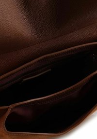 Bruine lederen handtas met textuur en meerdere compartimenten, voorzien van een donkere binnenkant en contrasterende stiksels langs de randen.