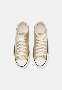 Zapatillas de cordones metálicas doradas con cordones blancos, puntera de goma y ribete negro. Superficie texturizada y marca en la lengüeta.