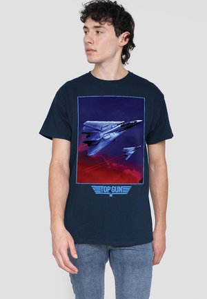 Dunkelblaues Baumwoll-T-Shirt mit einem Grafikmotiv von Kampfjets vor einem roten und lila Hintergrund, mit dem Text "TOP GUN" in Blau darunter.