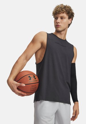 Black sleeveless athletic shirt with a loose fit, logo on chest, paired with gray shorts. Subject holds a basketball in one hand.