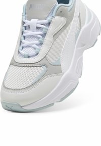 Chaussure de sport blanche et bleu clair en cuir et mesh, au design arrondi, avec col rembourré et semelle en caoutchouc texturée.