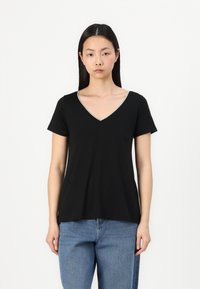 Black short-sleeve V-neck t-shirt with a soft texture and silver detailing around the neckline, paired with blue jeans.