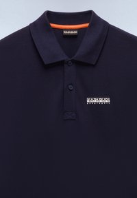 Marineblaues Polohemd mit zwei Knöpfen, orangem Kragenbesatz und dem Logo „Napapijri Geographic“ auf der linken Brust.