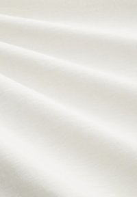 Gładki biały materiał z delikatnymi fałdami i subtelną teksturą, przedstawiony z bliska.