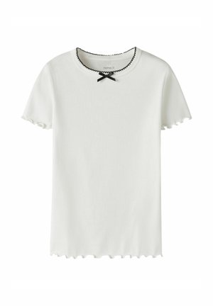 Biały prążkowany t-shirt z krótkim rękawem, z czarnymi falistymi krawędziami na kołnierzu, rękawach i dolnym brzegu, ozdobiony małą czarną kokardką przy dekolcie.