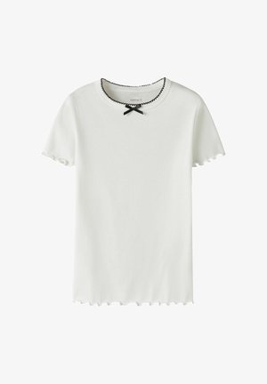 Λευκό ριμπ μπλουζάκι με κοντό μανίκι και μαύρες κυματιστές άκρες στο γιακά, τα μανίκια και το τελείωμα, με ένα μικρό μαύρο φιόγκο στον λαιμό.