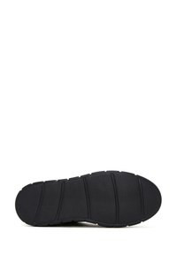 Semelle de chaussure en caoutchouc noir avec une surface texturée, dotée de rainures horizontales et de sections pour la flexibilité et l'adhérence.