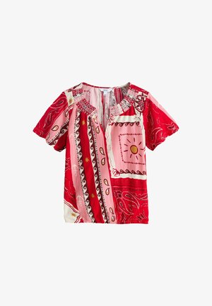 Kurzärmlige Bluse mit rot-, pink- und weißfarbenen Patchwork-Mustern, die Sonnen, Paisleys, Anker und einen Rüschenkragen zeigen.