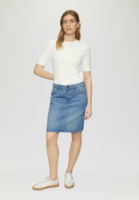 Lichte witte top met korte mouwen, gecombineerd met een aansluitende blauwe denim kokerrok, voorzien van een knoopsluiting aan de voorkant en subtiele stikdetails.
