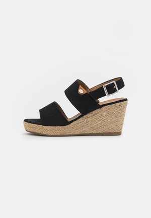 Zwarte suède wedge sandaal met twee brede banden en een gesp bij de enkel. Heeft een gestructureerd espadrille-stijl jute plateau.