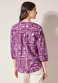 Camicia a maniche lunghe a righe viola e bianche con un design geometrico, maniche arrotolate, dettagli a pieghe sul retro e una vestibilità rilassata.