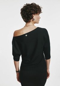 Czarny sweter bez ramiączek z rękawami o długości trzech ćwierć, charakteryzujący się gładką fakturą i okrąłym metalowym akcentem z tyłu.