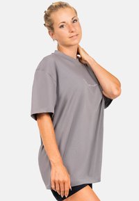 Grijze katoenen t-shirt met korte mouwen en een ontspannen pasvorm, gemaakt van zacht materiaal. Heeft een ronde halslijn en subtiele geborduurde tekst op de voorkant.