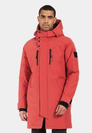 Parka imperméable rouge avec un col haut, une capuche ajustable, des poches poitrine zippées et des accents noirs. Présente des poignets élastiques et une coupe droite.