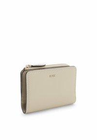 Beżowy skórzany portfel o gładkiej fakturze, z zamknięciem na zamek i widocznym logo. Prostokątny kształt z czystymi krawędziami i ozdobnym przeszyciem.