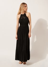 Vestido maxi negro con cuello halter, cuerpo texturizado y diseño de falda de volantes. Tela ligera con una silueta fluida y acentos minimalistas.