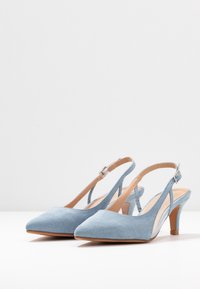 Escarpins slingback en daim bleu clair avec un bout pointu, un talon de hauteur intermédiaire et une sangle ajustable avec une boucle en métal argenté.