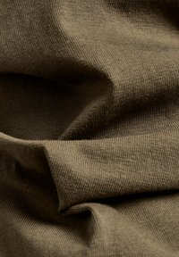 Brun ribbad tyg med mjuk textur och milda veck som indikerar flexibilitet och rörelse. Slät yta med ett konsekvent mönster.