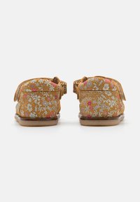 Geel met bloemmotief schoenen met een bovenwerk van textuurstof en een platte rubberen zool. Heeft een klittenbandsluiting en een zachte, gevoerde achterkant.