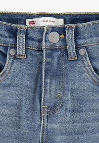 Jeans de mezclilla azul claro con un diseño de corte amplio y tapered, que cuentan con cinco bolsillos, costuras visibles y un cierre de botón plateado. Incluye etiqueta "Levi's".