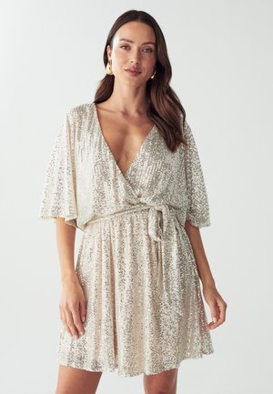Sparkly wrap dress in light beige with short flutter sleeves, a deep V-neck, and a tied waist. Features shimmering sequins throughout.