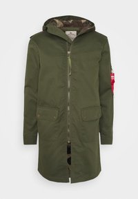 Chaqueta verde oliva de longitud media con capucha, cremallera frontal, dos grandes bolsillos delanteros y un forro de camuflaje. Presenta una etiqueta roja en la manga.