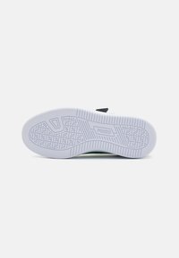Witte sneakerzool met een gestructureerd grippatroon, voorzien van een gladde rubberafwerking en een prominent logo. Zwarte accent nabij de hiel.