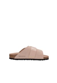 Sandales Birkenstock avec une tige en daim rose pastel et un détail de sangle brillant. Semelle en liège et semelle en caoutchouc noir, avec un matériel doré minimal.